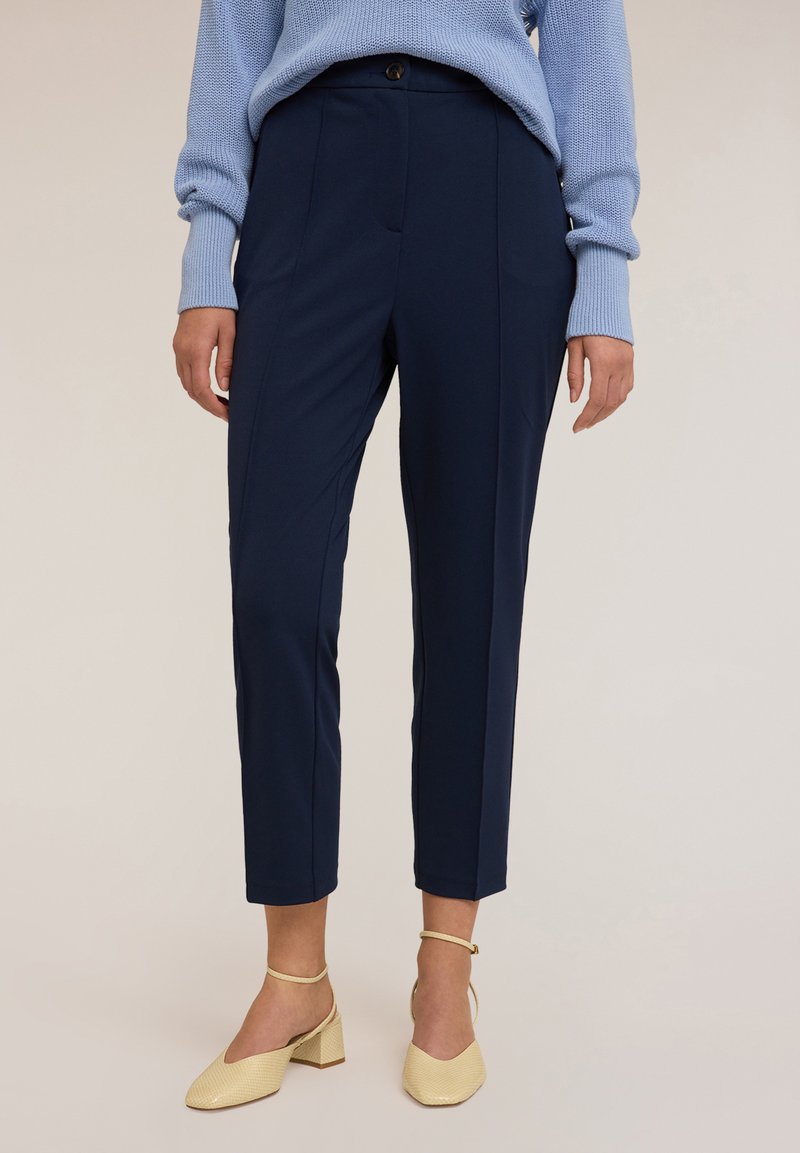 Námořnické kalhoty na míru s úzkým střihem, které mají jedno knoflíkové zapínání a přední kapsy, spárované se světle žlutými botami na blokovém podpatku.