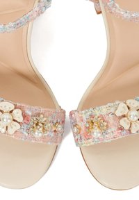 Roze en pastel geklede sandalen met een stevige band versierd met bloemmotieven, parels en gouden accenten op een beige zool.