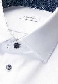 Hvid skjorte med mørke knapper og navyblåt kravefor med hvide prikker, mærket "seidensticker" på indersiden af kraven.