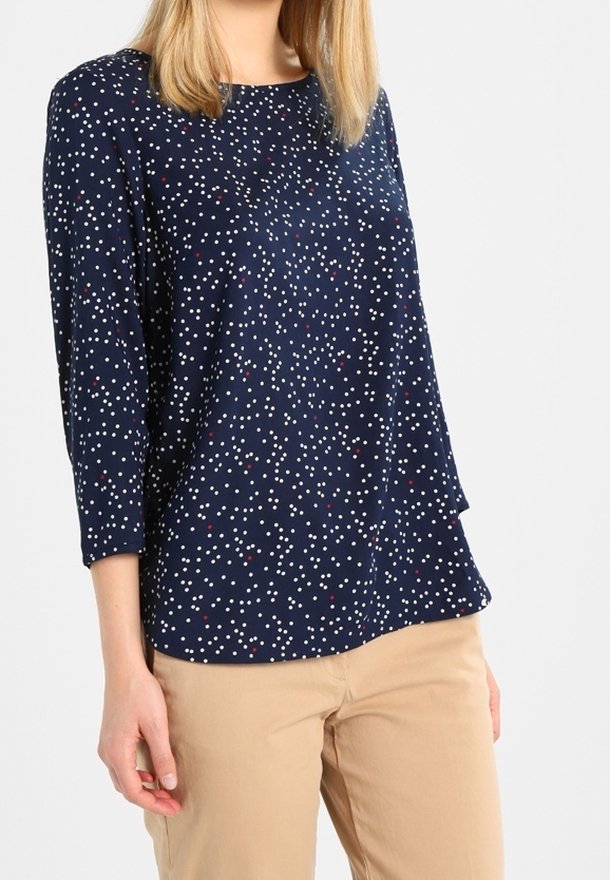 Top blu navy con maniche a tre quarti e scollo rotondo, caratterizzato da un motivo a pois bianchi e rossi distribuiti casualmente, realizzato in un tessuto liscio.