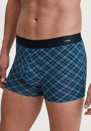 Boxer-briefs à carreaux bleus et noirs avec une ceinture élastique douce portant le nom de la marque "CALIDA", fabriqués en tissu lisse.