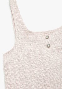 Vaaleanpunainen tweed-mekko, jossa on teksturoitu kudonta, leveät hihnat ja kaksi koristepainiketta, joissa on tekopearl-akorit kaula-aukossa.