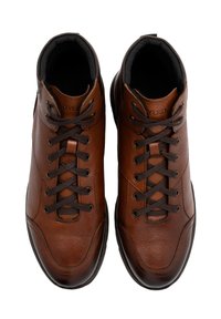 Brązowe skórzane buty wysokie z okrągłymi noskami, kontrastowym przeszyciem i płaskimi brązowymi sznurowadłami. Czarna podszewka i gumowa podeszwa.