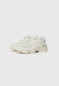 Baskets de sport blanches au design imposant, fabriquées en cuir lisse et en mesh. Présentent des accents texturés et une semelle en caoutchouc épaisse.