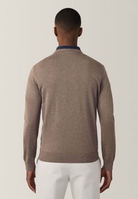 Brauner Strickpullover mit langen Ärmeln, rundem Ausschnitt, gerippten Bündchen und Saum, der eine glatte Textur und ein minimalistisches Design aufweist.