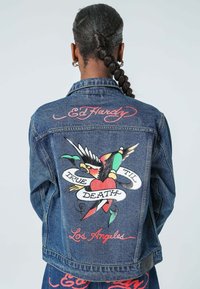 Chaqueta de mezclilla con diseño bordado colorido que presenta un pájaro, un corazón y el texto "True 'Til Death" y "Los Ángeles" en la parte trasera.