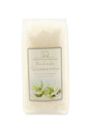 White bath salt package with a translucent front. Label features green floral design and simple text. Material appears granular and crystalline.