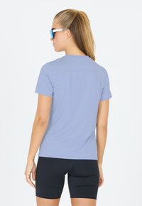 Maglietta atletica azzurro chiaro a maniche corte, con una texture liscia e una vestibilità comoda, abbinata a pantaloni corti neri aderenti, entrambi progettati per il comfort.