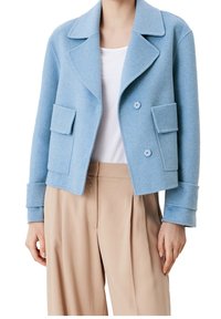 Ljusblå ochullblandad jacka med spetsig slag, dubbelknappslås och två framfickor med patch-fickor. Har uppvikt manschetter.