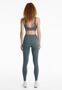 Tökéletes zöld sport szett, amely egy pántos sportmelltartóból és magas derekú leggingsből áll. Simább, rugalmas anyag, amelyen nincsenek látható minták vagy fém alkatrészek.