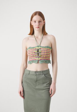Top court au crochet vert avec des rayures rose et jaune, présentant un ourlet en forme de vagues et une découpe centrale. Équilibré avec une jupe ajustée vert olive.