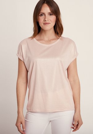 Haut rose clair à manches courtes avec un col rond et des poignets roulés, fabriqué dans un tissu doux, légèrement brillant, avec une texture lisse.