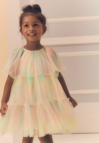 Robe en tulle pastel avec un design superposé, des manches courtes et des accents volantés. Présente un effet de couleur irisé dans des teintes douces.