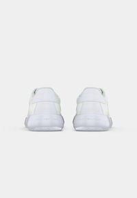 Witte sneakers met een glad leren bovenwerk en gaasdetails. Voorzien van een rubberen zool en een logo op de hak. Achteraanzicht toont een afgerond ontwerp.