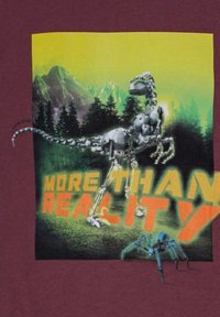 Burgundy t-paita, jossa on graafinen kuva robottidinosauruksesta värikkään taustan päällä. Edessä on boldatut oranssit kirjaimet "MORE THAN REALITY" ja sininen hämähäkki.