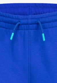 Modrá tepláková souprava s elastickým pasem a nastavitelným šňůrkem, který má tyrkysové plastové konce.