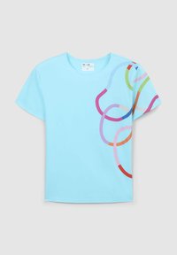 T-shirt in cotone azzurro chiaro con linee curve sovrapposte colorate in rosa, rosso, verde e blu sul lato sinistro. Maniche corte, scollo rotondo.