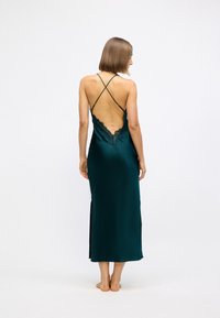 Abito slip in satin teal con design della schiena in pizzo, spalline sottili incrociate e taglio di lunghezza media, con una spacco laterale per facilitare i movimenti.