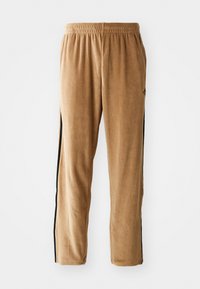 Calças de jogging em veludo tan com cintura elástica e riscas laterais pretas, apresentando um corte descontraído e textura suave.