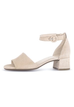 Beżowy zamszowy sandał z odkrytymi palcami, paskiem wokół kostki i szerokim obcasem. Charakteryzuje się gładką fakturą i regulowaną klamrą.
