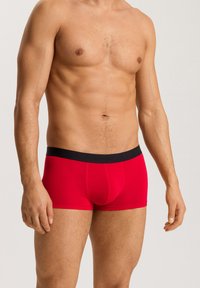 Boxer in rosso realizzati in un materiale liscio ed elastico, con una vita nera che presenta in modo discreto il nome del marchio "HANRO".