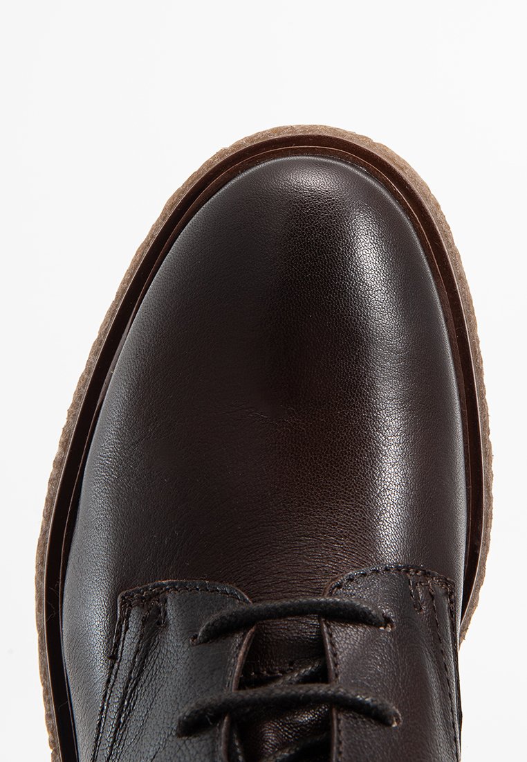 Braunes Leder-Schuh mit glatter Oberfläche, runder Zehenpartie, Schnürdesign und strukturiertem Gummisohle. Verfügt über einen kontrastierenden hellen Rand um die Sohle.