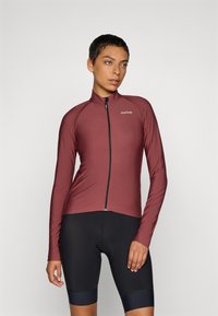 Bordeaux langermet sykkeljakke med glidelås, sømløst skulderdesign og mykt stoff. Brukt sammen med svarte sykkelshorts.
