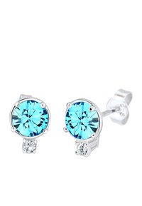 Boucles d'oreilles en studs en forme de pierres rondes bleues avec un petit accent en pierre claire, montées sur un métal de couleur argentée. Les pierres bleues ont une taille à facettes.