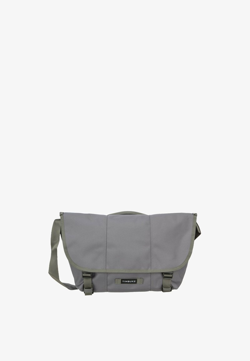 Sac messager gris Timbuk2 avec bandoulière réglable, rabat avant, deux fermetures à boucle et étiquette de marque au centre avant.