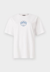 Balta kokvilnas T-krekls ar zilu dekoratīvu etiķetes grafiku, kas centrā uz krūtīm ir uzraksts "Moschino Jeans Hotel". Īsas piedurknes.