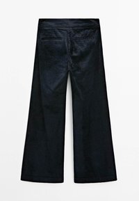 Pantaloni neri in corda a gamba larga con un tessuto testurizzato, due tasche posteriori e una cintura. Il design presenta linee pulite e nessun hardware visibile.