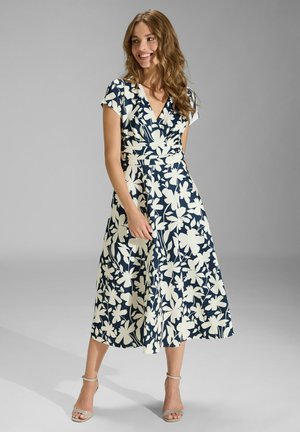 Blumenmuster Kleid in Marineblau und Creme, mit V-Ausschnitt, kurzen Ärmeln und tailliertem Bund. Fließender Midilängenrock mit glatter Textur.