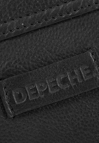 Czarna skórzana łatka z wytłoczonym logo "DEPECHE", charakteryzująca się teksturowaną powierzchnią i widocznymi szwami wzdłuż krawędzi.