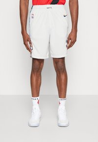 Shorts de basketball blancs avec une taille élastique, arborant le logo de la NBA, le nom de l'équipe et des accents latéraux contrastants. Portés avec des baskets blanches et des chaussettes.