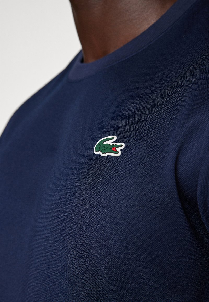 T-shirt in cotone blu navy con finitura testurizzata e logo coccodrillo ricamato in bianco, verde e rosso sul petto sinistro. Design con colletto tondo.