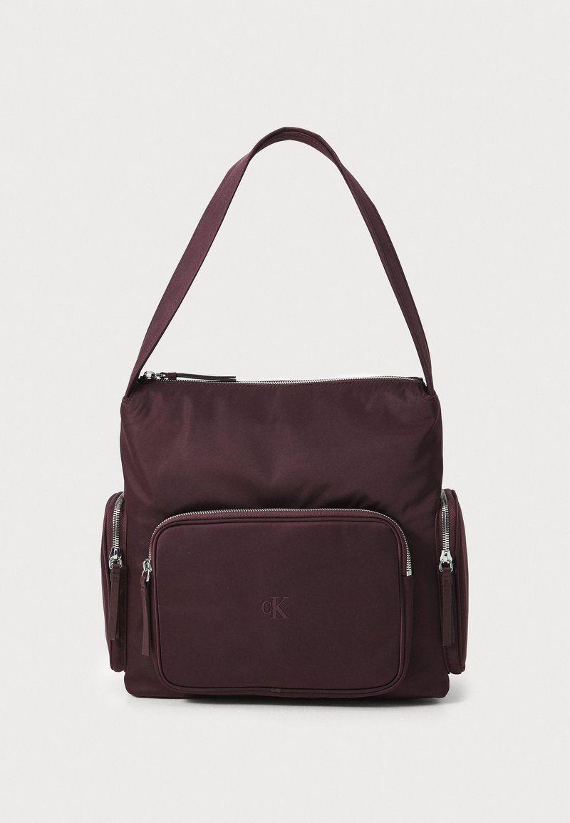 Borsa a spalla in tessuto bordeaux con zip superiore, due tasche laterali e compartimento frontale. Caratterizzata da un logo e da una tracolla regolabile.