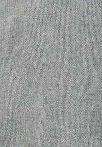 Jasnoszary dzianinowy materiał o fakturowanym wzorze, ukazujący mieszankę włókien i subtelne zróżnicowanie odcieni na całej powierzchni.