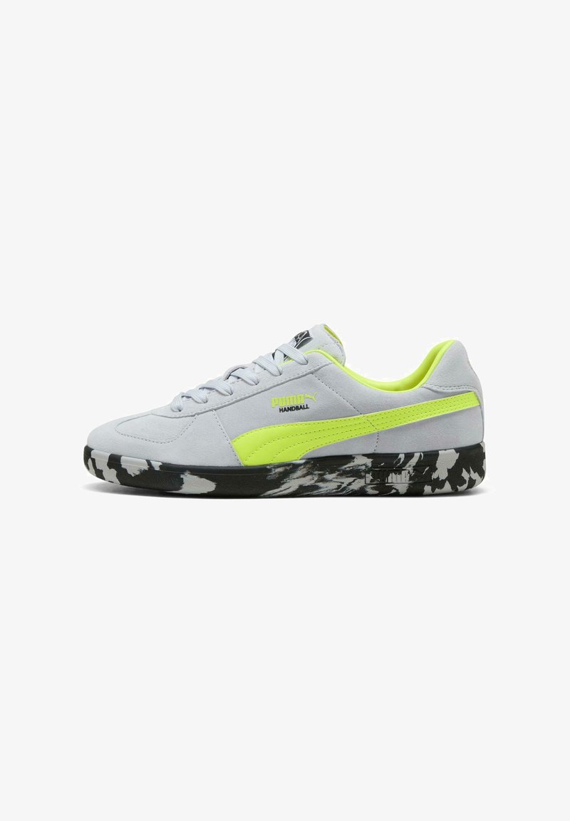Chaussure de handball Puma gris clair avec bande néon jaune et intérieur assorti, semelle à motif noir et blanc, design bas à lacets.