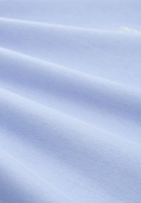 Lys blå stof, blød tekstur og glat overflade, med subtile linjer og lette folder der skaber dybde. Minimal mønster, ensartet farve.