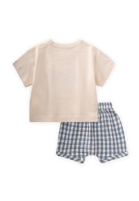 Camiseta de algodón color beige claro con mangas cortas, combinada con pantalones cortos de cuadros a rayas en azul y blanco. Tejido suave, diseño informal, cinturilla elástica.