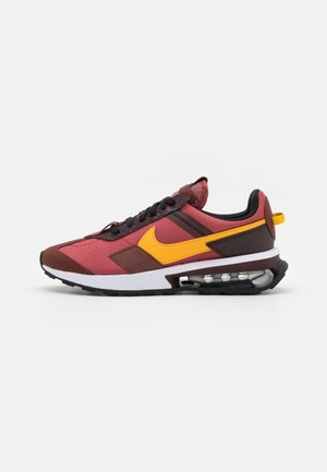 Herre atletisk sneaker i rød og brun med gul Nike swoosh og synlig luftstød i sålen på hvid baggrund.