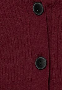 Burgunderfärgad cardigan med vertikal ribbning, centrerade svarta knappar och ett mjukt, strukturerat material.