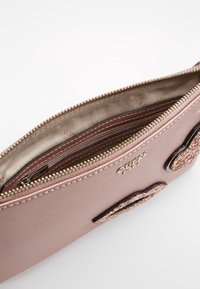 Reißverschlusstasche in Rosaton aus strukturiertem Material, mit gefüttertem Innenraum und Fächern sowie dekorativen Akzenten außen.