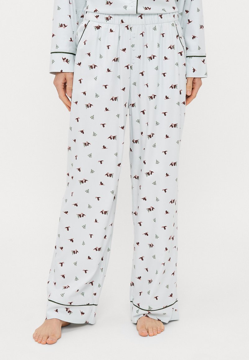 Witte pyjamabroek met een herhalend patroon van kleine vogels en groene bomen, met een ontspannen pasvorm, een elastische tailleband en contrasterende bies.