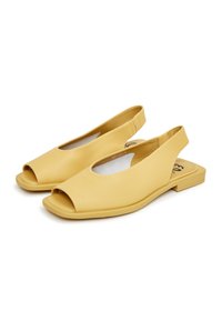 Keltainen nahkainen slingback-kengät, joissa on avonaiset varpaat, tasapohja ja tyylikäs muotoilu. Ominaisuuksiin kuuluvat leikkaukset ja sileä pinta.