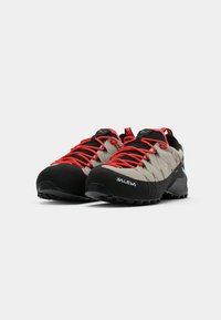 Leichte Wanderschuhe mit einem grauen Obermaterial aus Stoff, einer schwarzen Gummispitze und leuchtend roten Schnürsenkeln. Strukturiertes Profil für Grip und Stabilität.