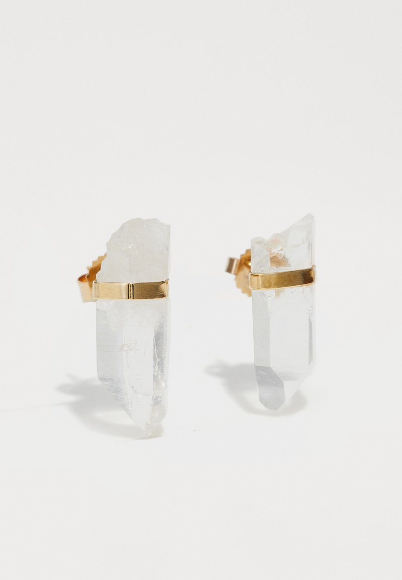 Dva ušesna uhani iz prozornega kvartsnega kristala z zlatimi trakovi. Kristali imajo nepravilno obliko z ostrimi robovi, ki prikazujejo naravne teksture.