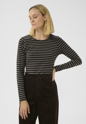 T-shirt à manches longues avec des rayures horizontales noires et grises, fabriqué en tissu doux. Associé à un pantalon en velours côtelé marron taille haute.