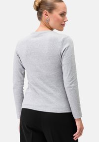 Langärmliges graues T-Shirt aus weicher Baumwolle mit rundem Halsausschnitt und figurbetonter Silhouette. Minimalistisches Design, keine sichtbaren Muster.