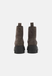 Pruunist nubukist pahkluu saapad, millel on tumesinine chunky tald, taga tõmblukud ja siledad külgpaneelid. Puhas disain minimalistikest detailidest.